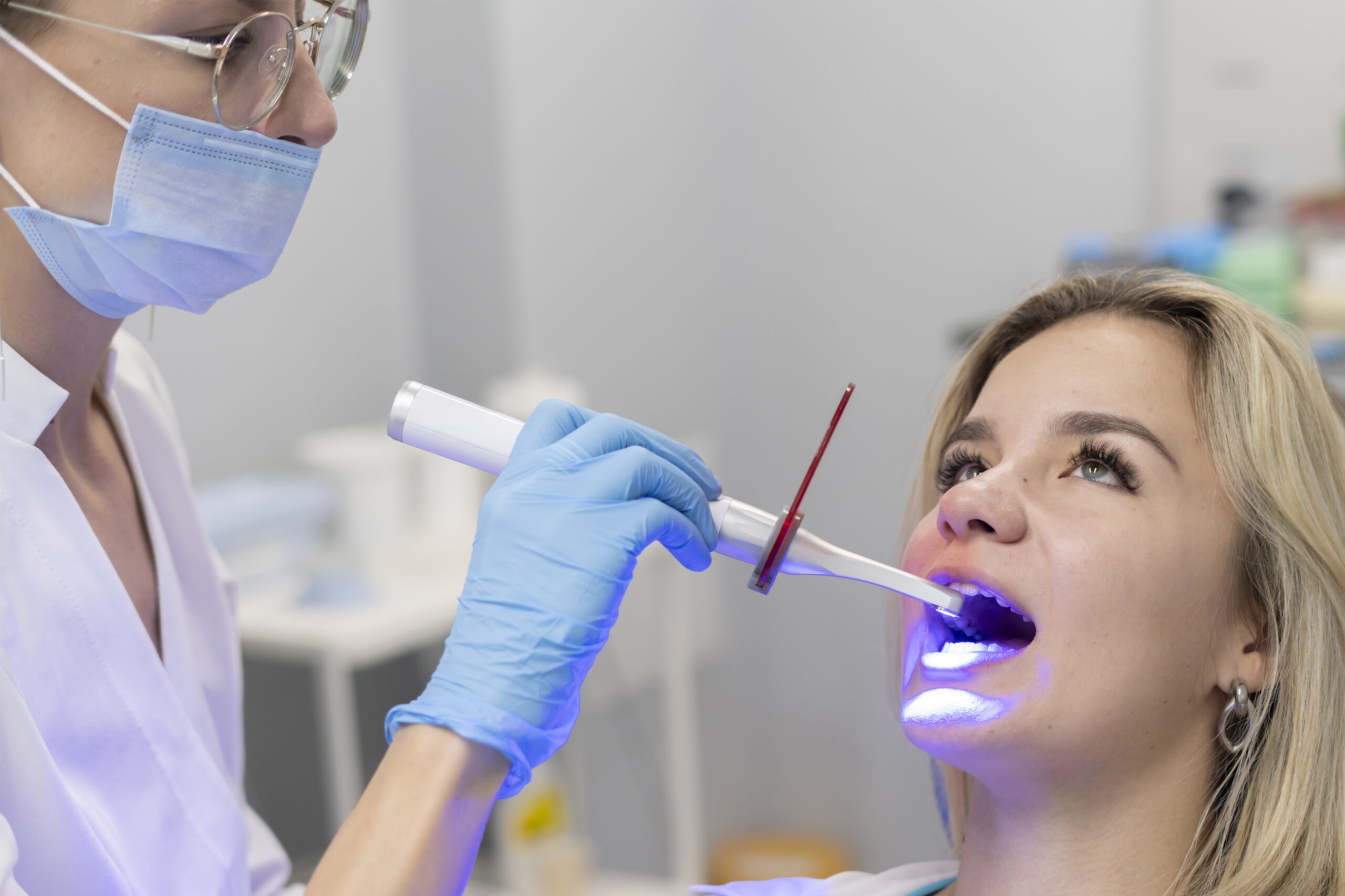 young girl on a teeth whitening treatment, using ultraviolet lamp for bleaching